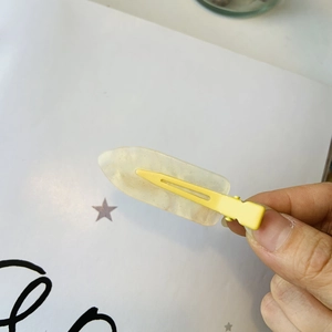 Dettaglio di un fermaglio per capelli in resina giallo tenue con glitter dorati