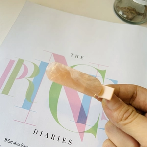 Gros plan détaillé d'une pince à cheveux rose marbrée avec paillettes sur un magazine