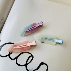 Dettaglio di tre fermagli per capelli in resina color macaron con trama marmorea e glitter