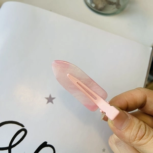Dettaglio della clip per capelli rosa marmorizzato con glitter oro e acrilico