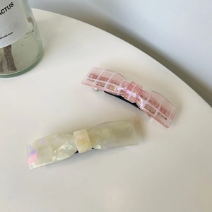 Détail de barrettes à cheveux en acétate à carreaux roses et nacre sur fond blanc