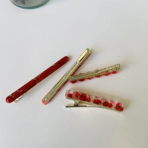 Detail of 4-piece red hair clip set with marble texture, gold metal, and dried flowers