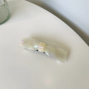 Vue détaillée d'une pince à cheveux en acétate nacré avec des reflets irisés violets