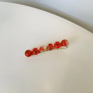 Elegant floral hair clip with red dried flowers inside transparent beads on gold base