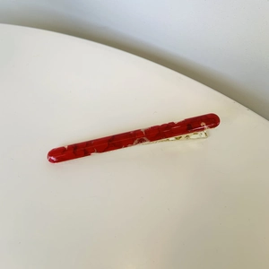 Detail view of long dark red marble resin hair clip with elegant golden metal base