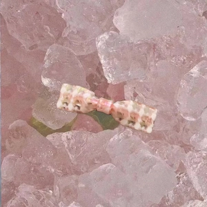 Barrette à cheveux nœud en acétate fleuri rose et vert sur un fond de glaçons