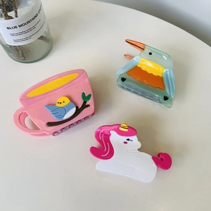 Close-up of acetic acid hair claws featuring bird, coffee cup, and unicorn shapes
