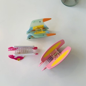 Detailed top view of three colorful acetate hair claws featuring bird and butterfly designs