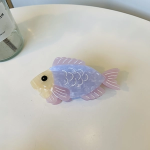 Dettaglio della molletta per capelli a forma di pesce in acetato con trama marmorizzata