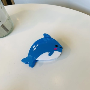 Dettaglio di una graziosa pinza per capelli a balena blu in acetato lucido