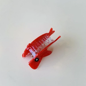 Vista macro di un fermaglio per capelli a forma di gambero rosso in acetato di cellulosa