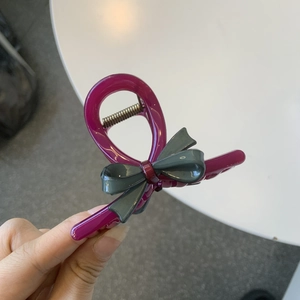 Detail view of pink bow hair claw with green accents and durable metal spring