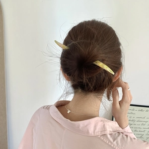 Pic à cheveux élégant avec motif marbre pour femme porté dans un chignon brun