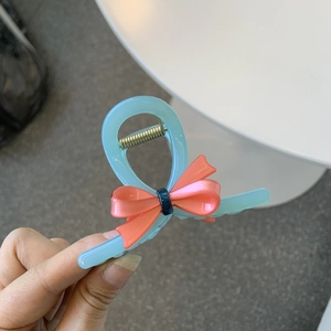 Detailed view of acetate bow hair claw clip in light blue and coral pink finish