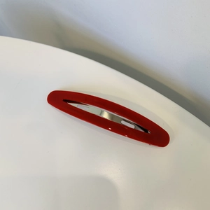 Vue détaillée de la pince à cheveux ovale en acétate rouge brillant et base métal