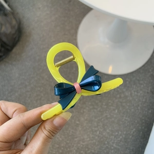 Close-up of contrast yellow acetate hair claw with deep blue bow and pink center detail