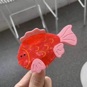 Dettaglio della molletta per capelli a forma di pesce rosso in acetato lucido