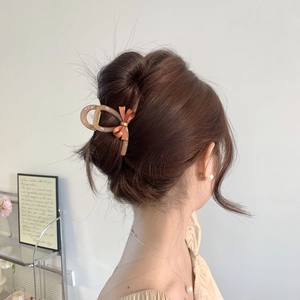Detail of elegant bow acetate hair claw clip worn on hair in a cozy indoor setting