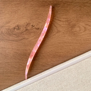 Détail d'un pic à cheveux en acétate rose à motif marbré avec design élégant en S