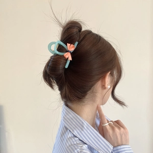 Blue bow hair claw clip styled on a brown hair bun with sweet and elegant aesthetic