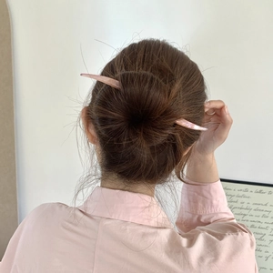 Pic à cheveux minimaliste en acétate rose clair porté dans un chignon élégant