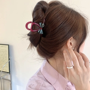 Elegant burgundy hair claw with blue bow clip shown on a high-volume hair bun