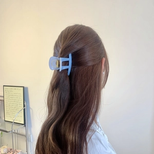 Pince à cheveux géométrique bleu givré portée sur une coiffure demi-attachée élégante