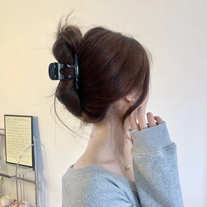 Gros plan d'une grande pince à cheveux noire brillante fixant une coiffure sur un modèle