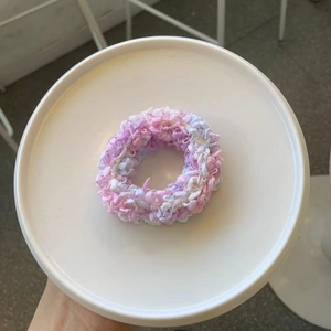 Schickes Strick-Haargummi in Pastellrosa, Lila und Weiß auf einem weißen Keramikteller