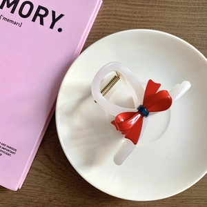 Detail of the translucent hair claw with a striking red 3D bow and strong metal spring