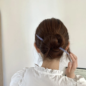 Vue détaillée d'une femme utilisant le pic à cheveux en acétate lilas pour un chignon