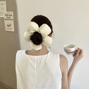 Gros plan d'un chouchou fleur en satin crème porté par un mannequin de style français