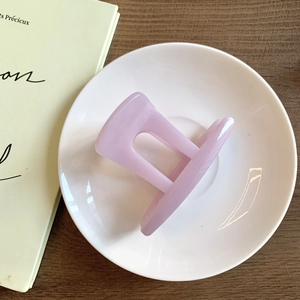 Détail d'une pince à cheveux rectangulaire violet clair sur une assiette blanche