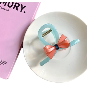 Elegant bow hair claw in blue and pink acetate with secure metal spring for women