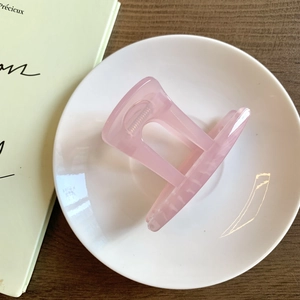 Vue détaillée d'une pince à cheveux rose translucide sur une assiette en céramique