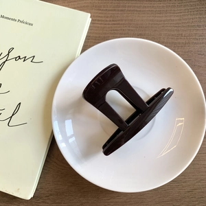 Détail d'une pince à cheveux géométrique en résine marron foncé sur assiette