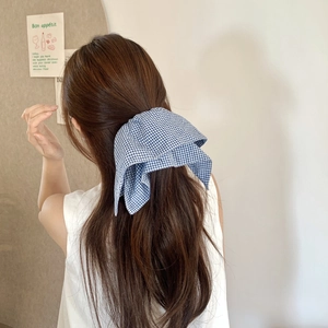 Rear view of a model wearing a large blue and white checkered bow hair scrunchie