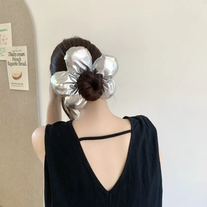 Détail d'un grand chouchou argenté métallisé avec texture plissée florale sur un chignon
