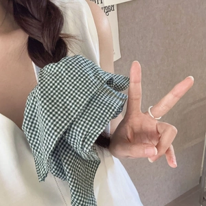 Detailed view of a green and white gingham checkered fabric scrunchie on a braided hairstyle