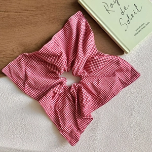 Close-up of a large red and white plaid scrunchie styled with vintage books