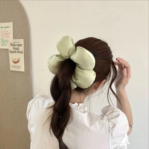 Chouchou bouffant en satin vert clair sur queue de cheval basse pour un style vintage