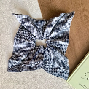 Detailed close-up of blue and white gingham large hair scrunchie on wooden background