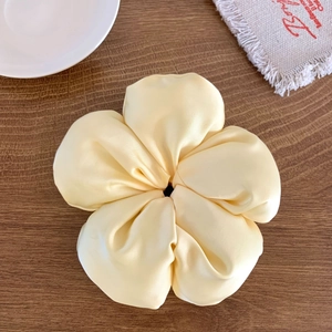 Gros plan d'un chouchou fleur en satin crème avec une texture de soie lisse