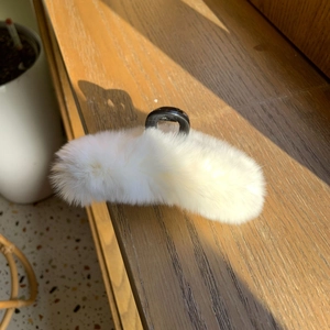 Gros plan d'une pince à cheveux en fausse fourrure blanche avec lumière naturelle douce