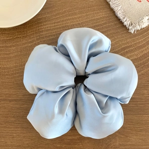 Détail d'un chouchou en satin bleu clair plié en forme de fleur sur fond de bois sombre