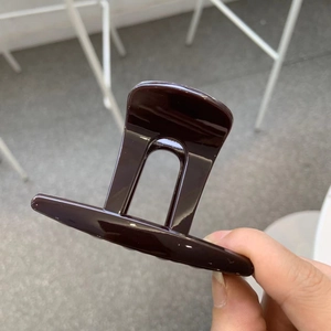 Détail de la pince à cheveux marron foncé brillant montrant sa finition et sa prise
