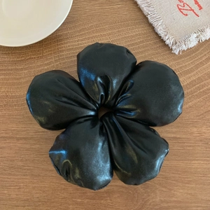 Gros plan du chouchou floral noir avec texture satinée sur table en bois