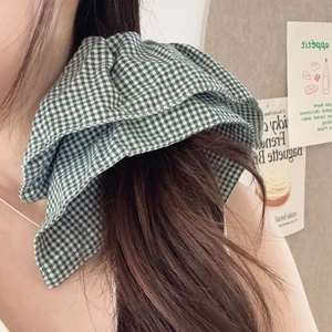 Green and white checkered large fabric scrunchie worn on wrist for trendy hair styling