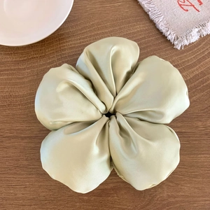 Gros plan d'un chouchou fleur en satin vert menthe avec texture soyeuse sur fond en bois