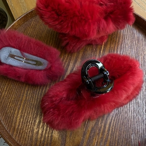 Detail von flauschigem rotem Kunstfell-Haarspangen-Set auf einem Vintage-Holztablett